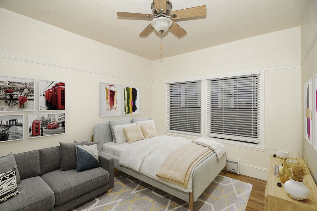 A bedroom with a bed, couch, and pictures on the wall.