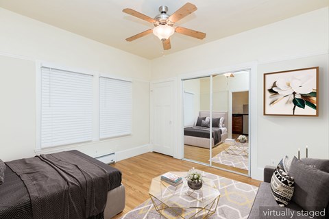 A bedroom with a bed, a couch, a ceiling fan, and a painting on the wall.