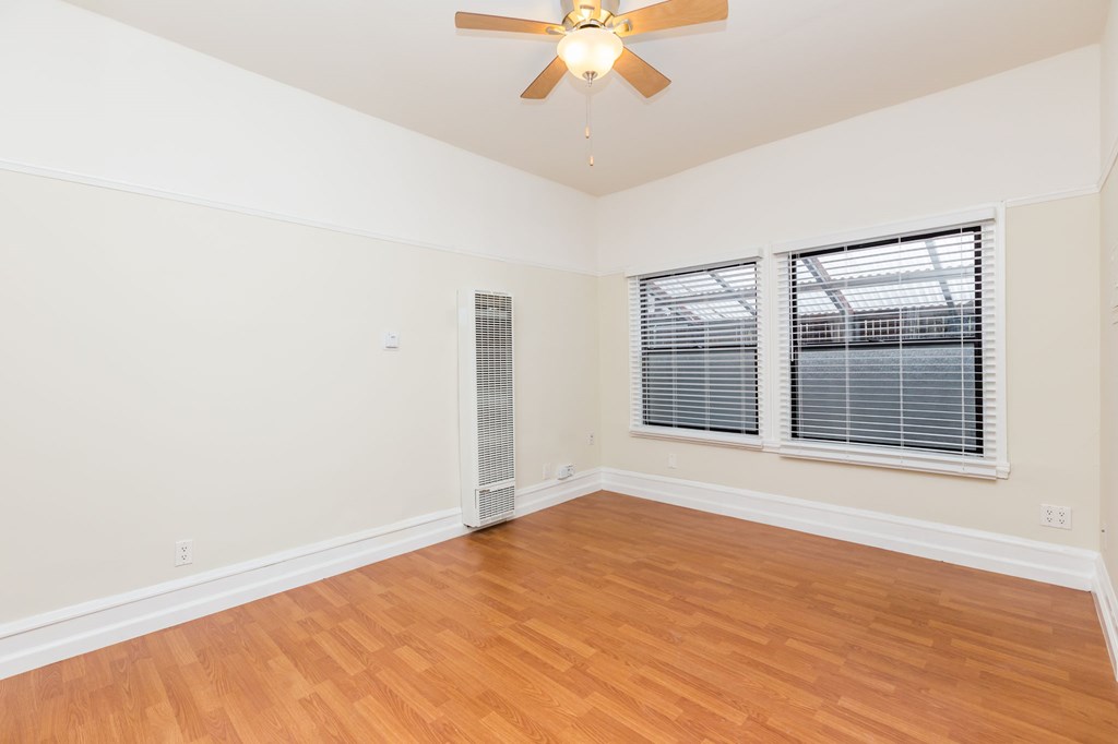 an empty living room with a window and a ceiling fan