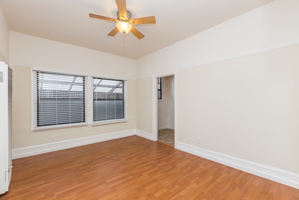 an empty living room with a ceiling fan and a window