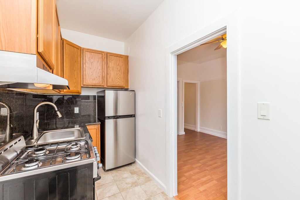 a kitchen with a stove and refrigerator and a door to a hallway