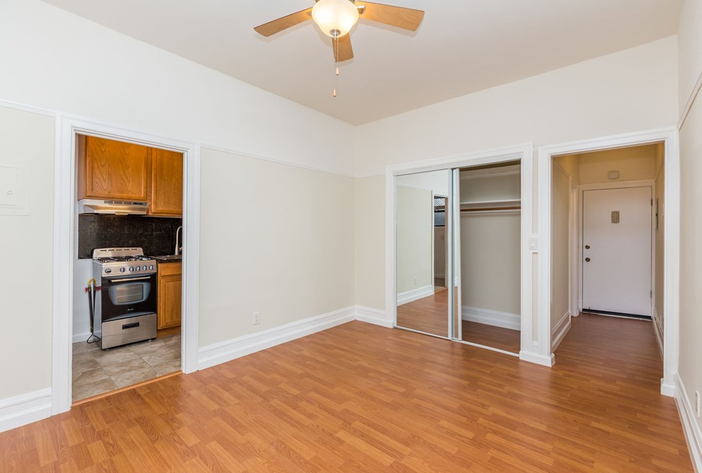 an empty living room with wood floors and a ceiling fan
