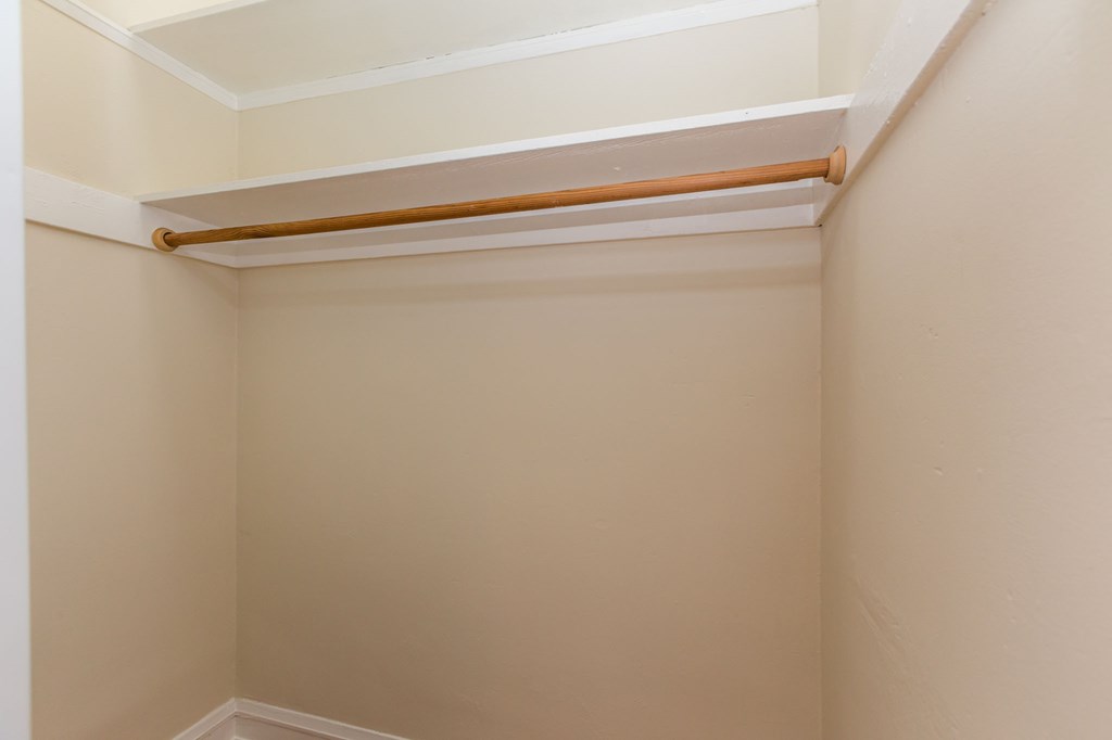 a small closet with a rail on the ceiling and a white wall