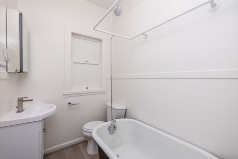 A white bathroom with a tub, sink, and toilet.