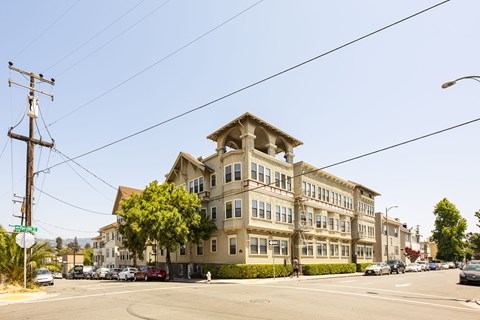 A large building with a tower on top sits on a street corner.