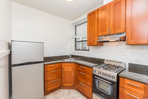 A kitchen with a black stove top oven and wooden cabinets.