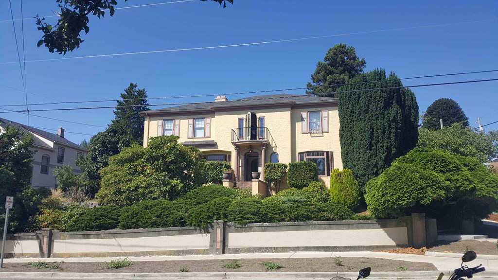 A yellow house with a white fence in front.