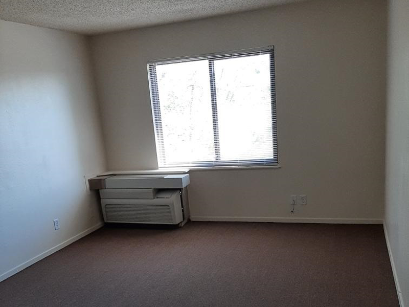an empty room with a window and an entertainment center