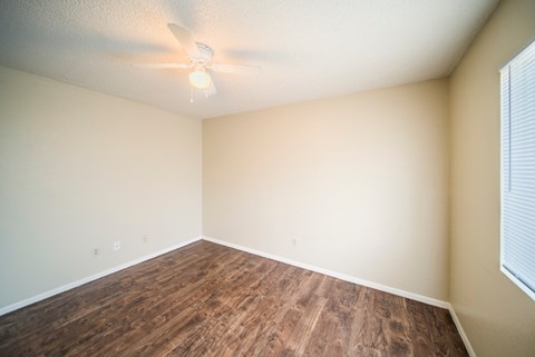 Empty room with wood flooring and a ceiling fan.