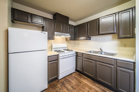 A kitchen with a white refrigerator and dark brown cabinets.