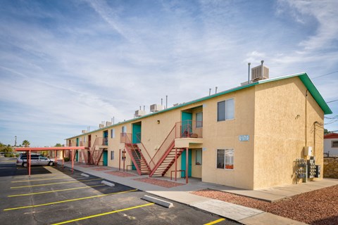 A building with a green roof and a parking lot in front.