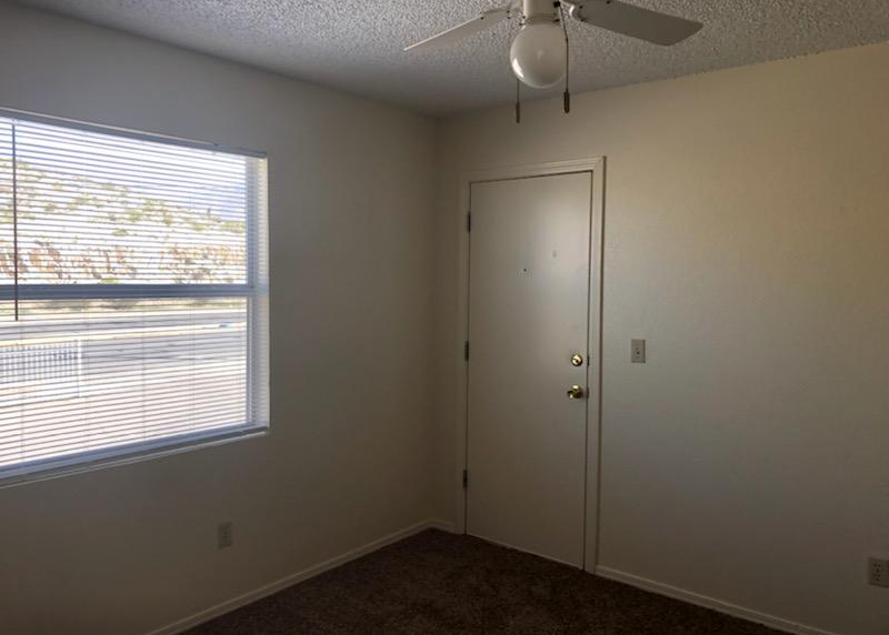 A room with a ceiling fan and a window with blinds.