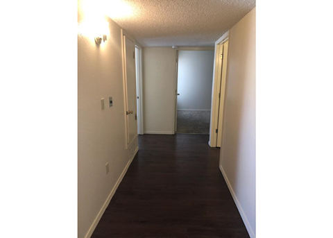 A hallway with a door on the right and a light on the wall.