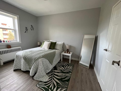 A bedroom with a bed, a small table, and a zebra rug.