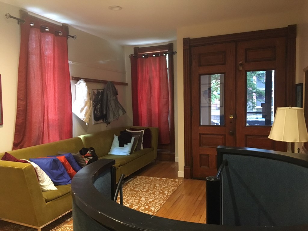 a living room with a couch and a door with red curtains