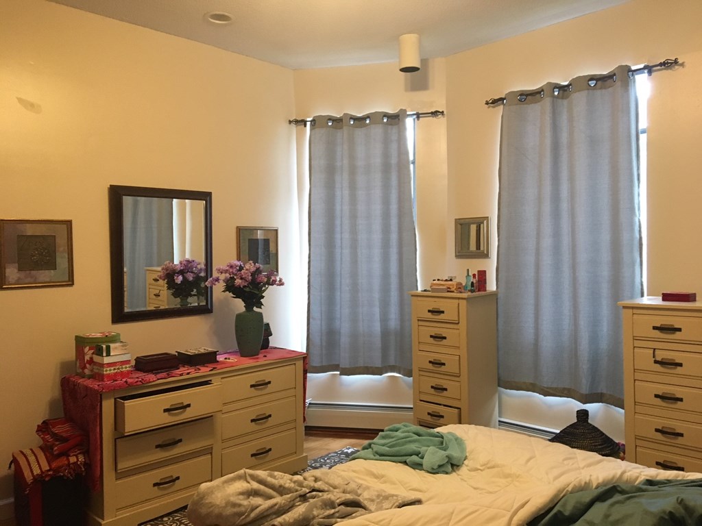 a bedroom with a bed and dressers and curtains
