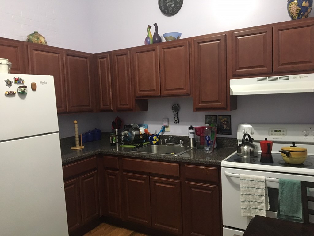 a kitchen with brown cabinets and white appliances and a sink