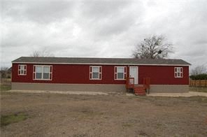 A red building with a grey roof and a white door.