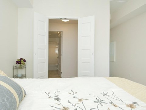 A bedroom with a large bed and a doorway leading to another room.