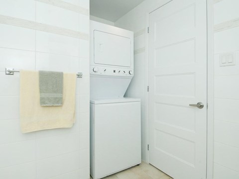A white bathroom with a towel hanging on the wall and a white door.