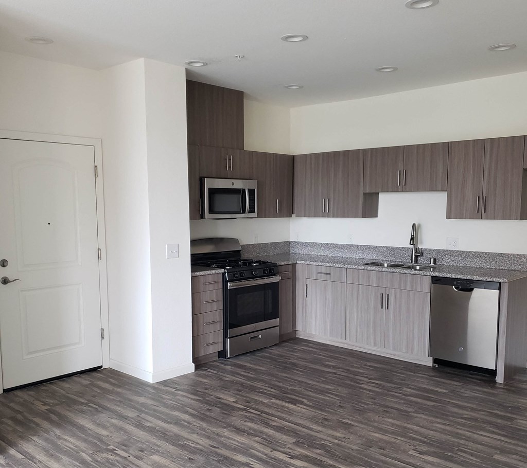an empty kitchen with wood flooring and stainless steel appliances