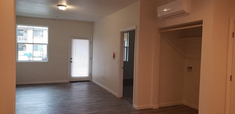 an empty living room with a door to a hallway and a window