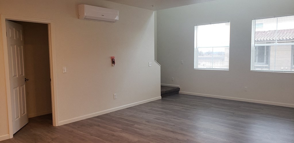 an empty living room with wood flooring and white walls