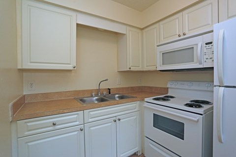 A kitchen with white cabinets and appliances.