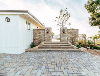 the entrance to a home with a stone wall and a stone patio