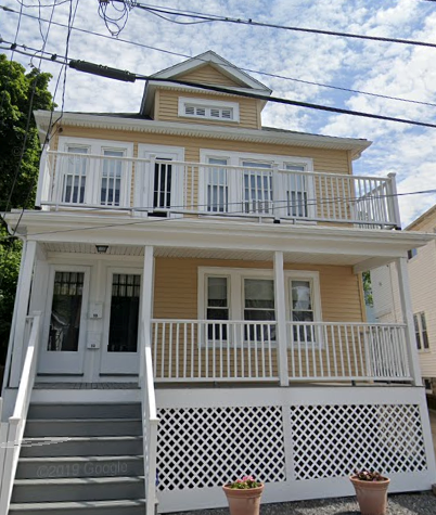 the front of a yellow house with a white porch