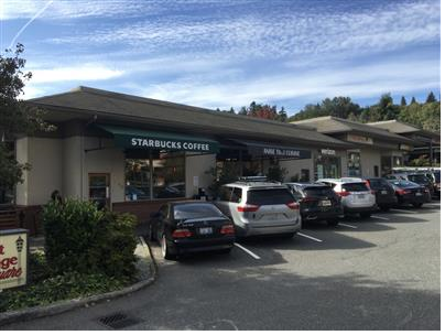 a starbucks coffee shop with cars parked in the parking lot