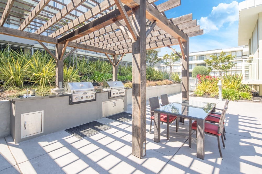 a patio with a dining table and barbecue grill