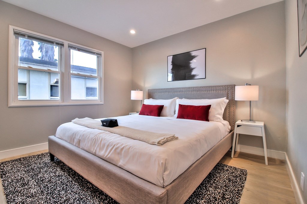 a bedroom with a large bed and two windows