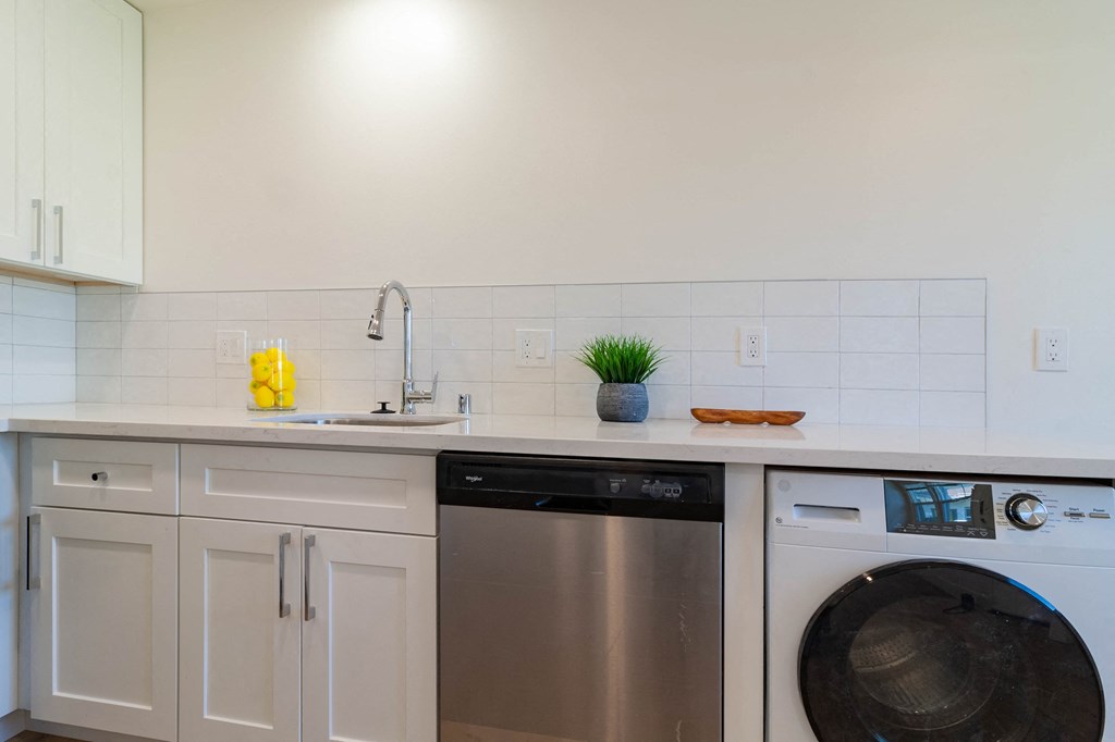 a kitchen with white cabinets and a washing machine and a sink