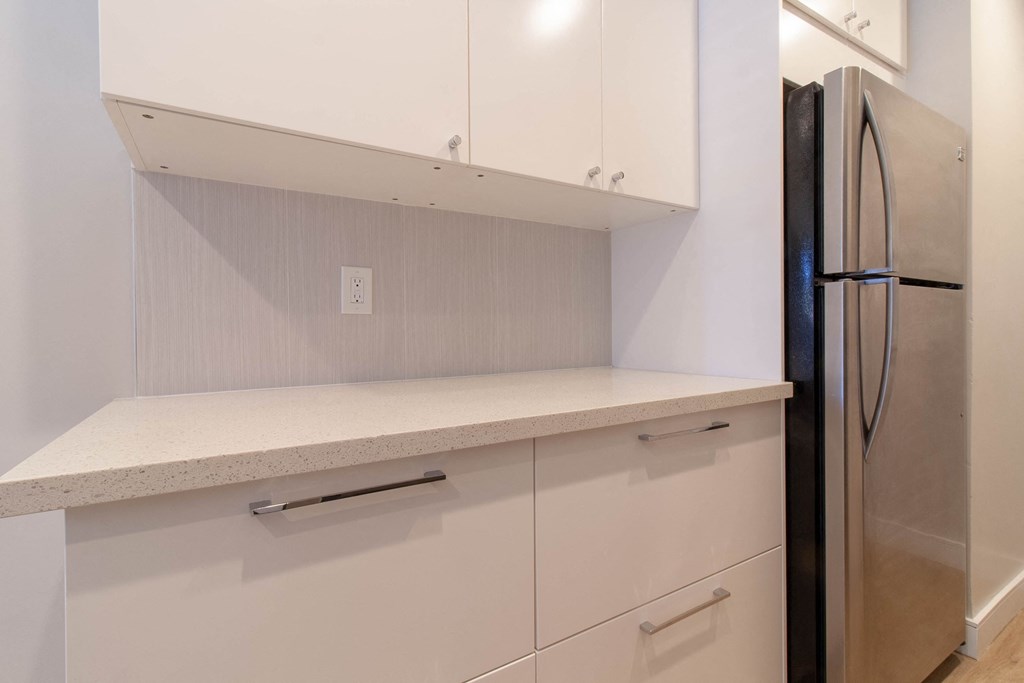 a white kitchen with white cabinets and a refrigerator