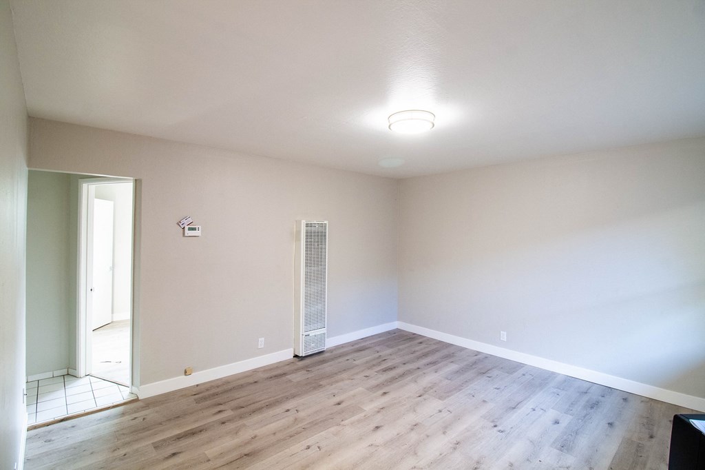 an empty living room with wood floors and white walls