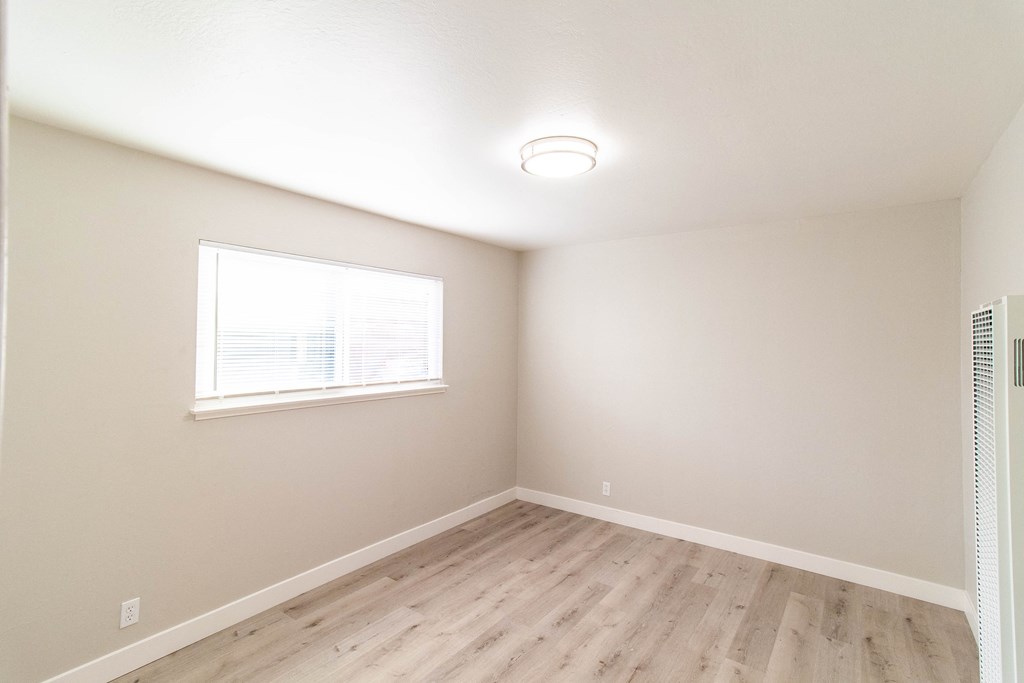 an empty room with wood floors and a window