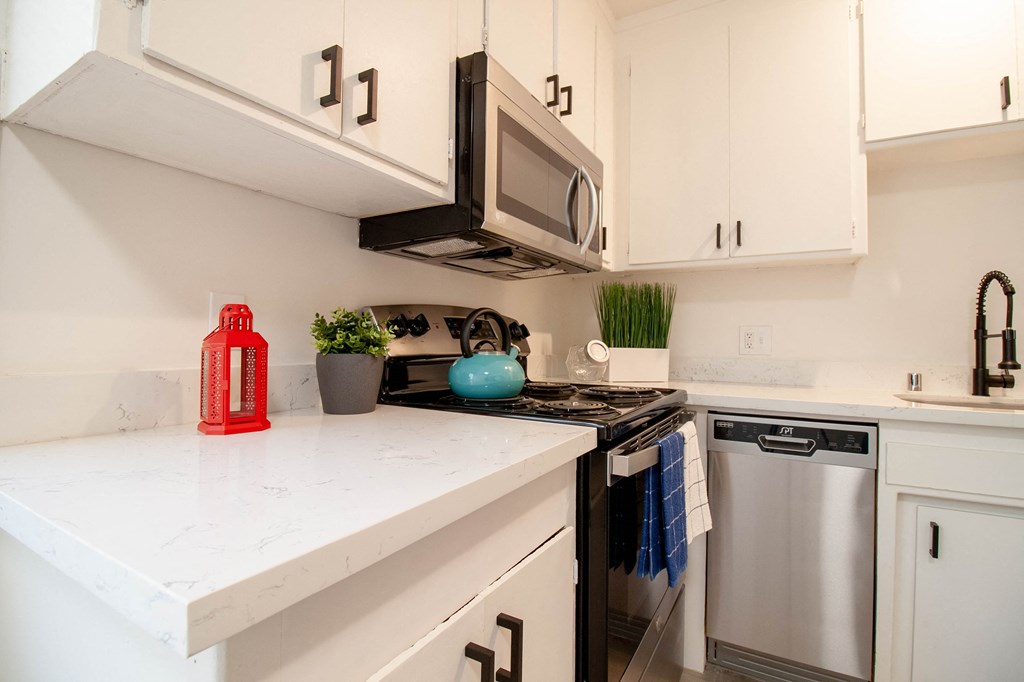 a kitchen with white countertops and a stainless steel oven and microwave