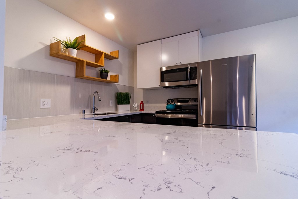 a modern kitchen with a marble floor and stainless steel refrigerator