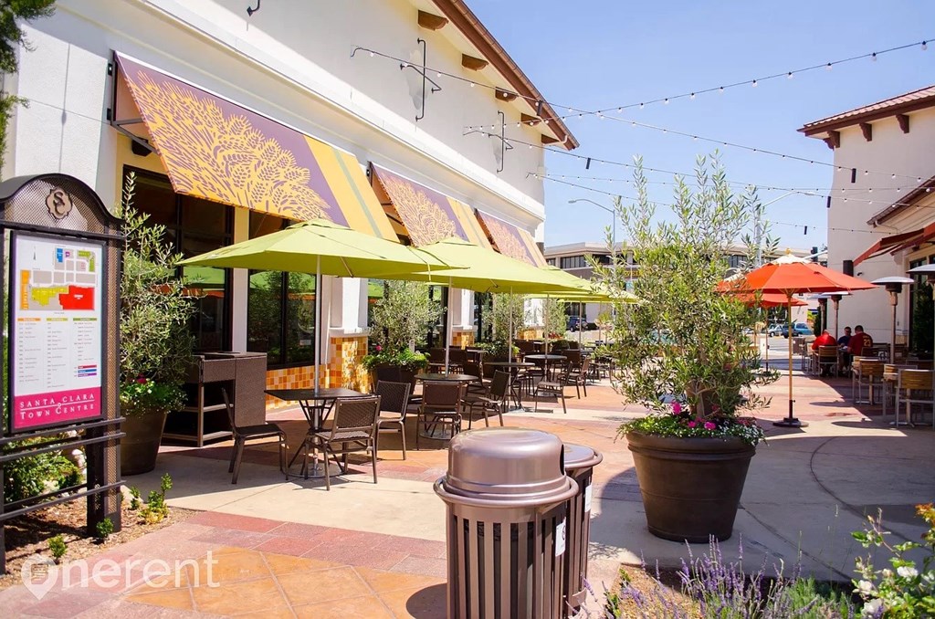 a patio with tables and umbrellas outside of a restaurant