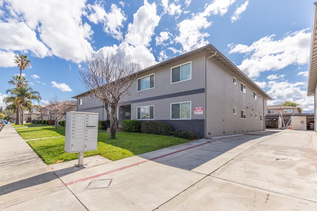 a gray and blue house with a sidewalk and grass