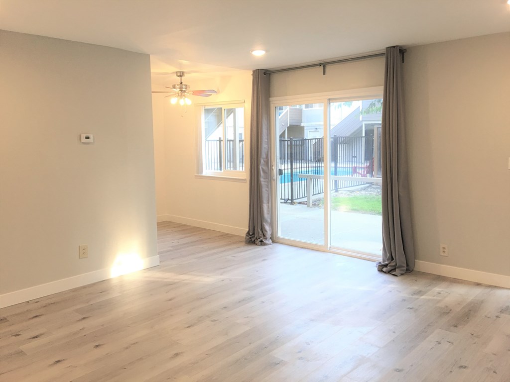 an empty living room with sliding glass doors to a backyard