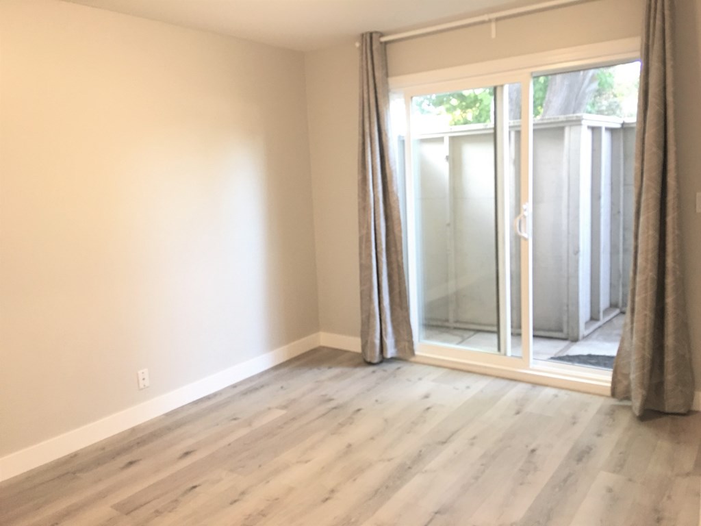 an empty living room with sliding glass doors to a balcony