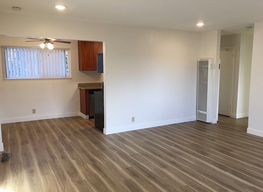 an empty living room with wood flooring and a ceiling fan