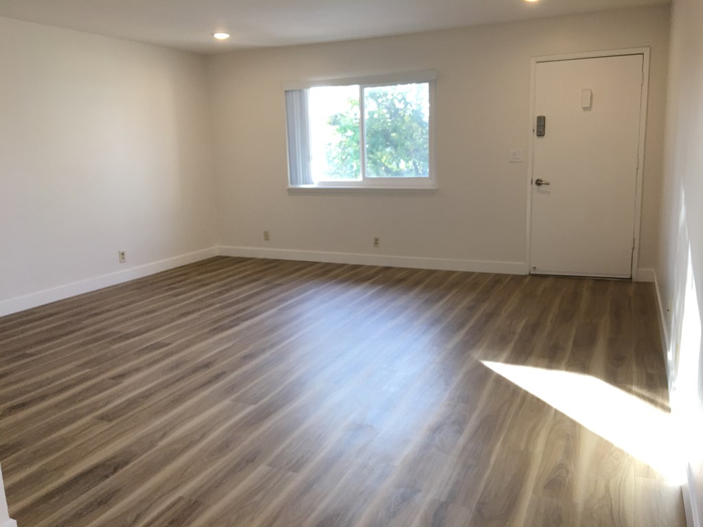 an empty living room with wooden floors and a window