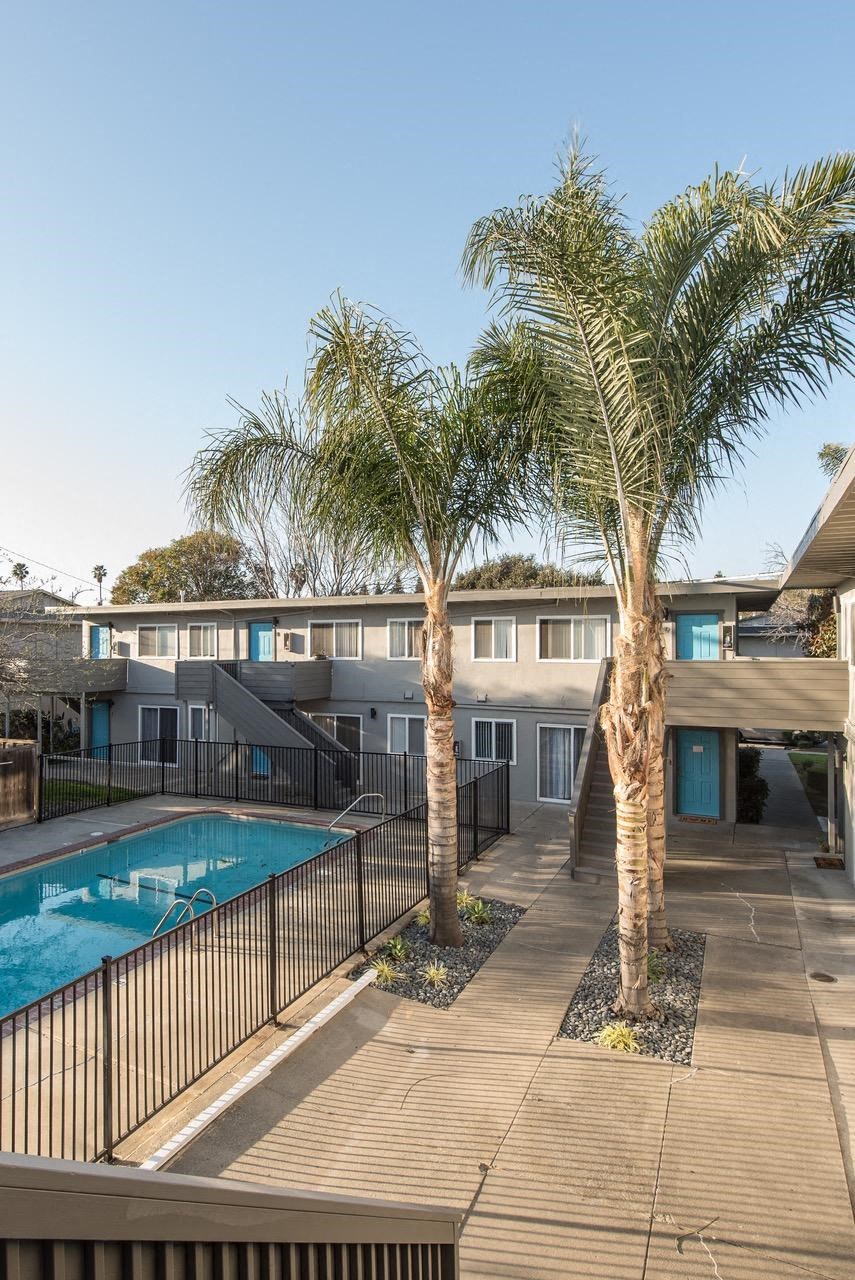 a building with a pool and palm trees in front of it