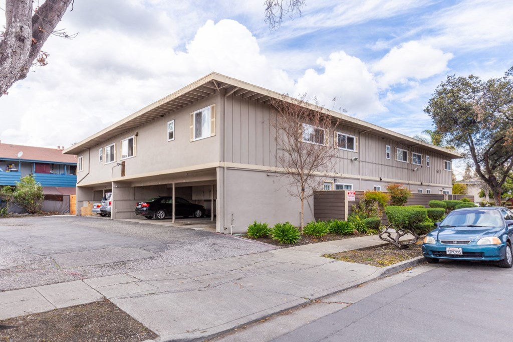 the exterior of an apartment building with cars parked outside