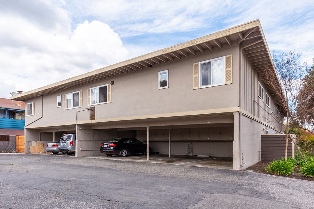 the front of a building with a parking lot and two cars