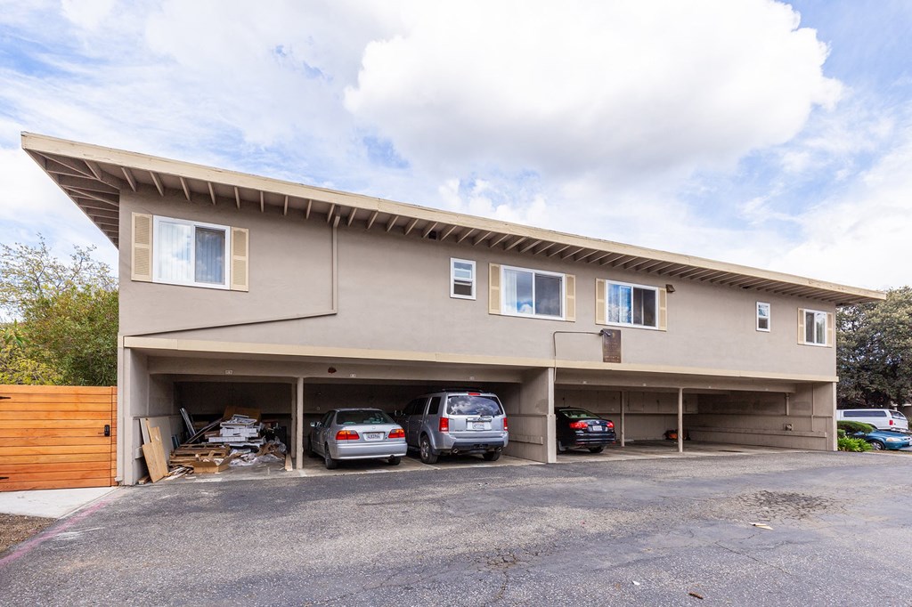 the front of a tan building with cars parked under it