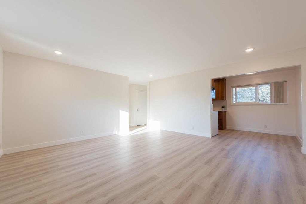 an empty living room with white walls and wood floors